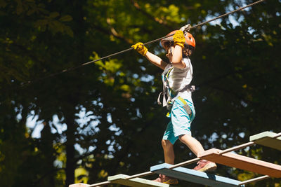 Full length of man holding rope against trees