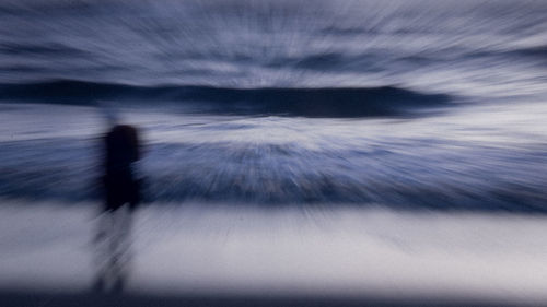 Defocused image of silhouette man walking against sky