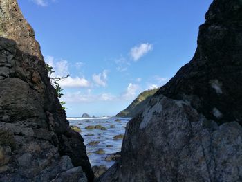 Scenic view of sea by mountains against sky