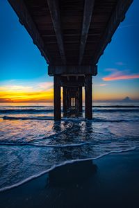 Bridge over sea against sky during sunset