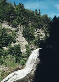 Scenic view of waterfall in forest against sky