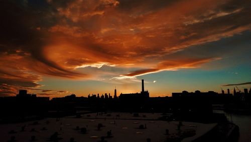 Cityscape against cloudy sky at sunset