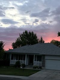 House by trees against sky at sunset