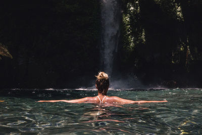 Rear view of shirtless man swimming in pool