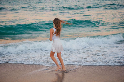 Rear view of young woman standing at beach