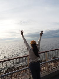 Rear view of man standing by railing against sea