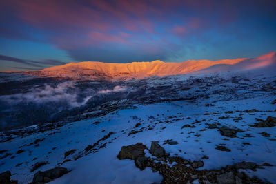 Scenic view of snowcapped mountains against sky during sunset