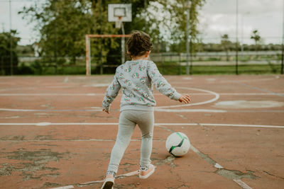 Rear view of woman playing soccer at park