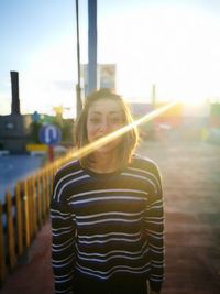 Portrait of smiling young woman standing at promenade on sunny day