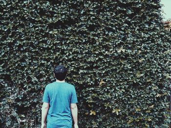 Rear view of a man standing against leaves