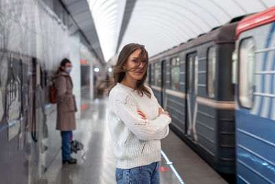 Woman in white sweater waiting for a train at a subway station