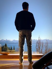 Rear view of man standing on snow against sky