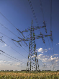 Low angle view of electricity pylon on field against sky