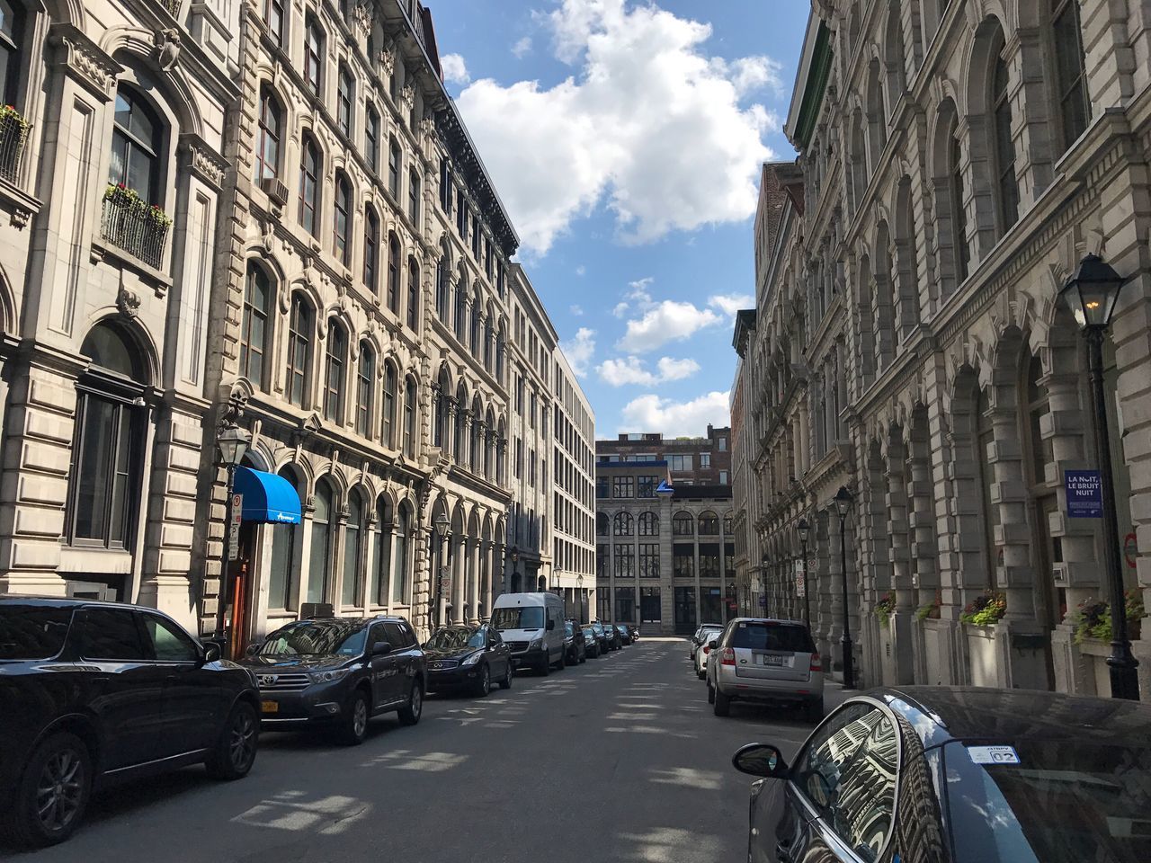 VEHICLES ON ROAD ALONG BUILDINGS