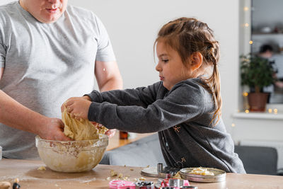 Father feeling playful with his caucasian little daughter, while preparing homemade dough 