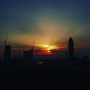 Silhouette of buildings against sky at sunset