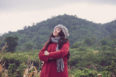 Woman in warm clothing standing against mountains