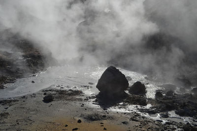 Geothermal hot spring with steam vapors rising up from it in iceland.