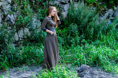 Portrait of young woman standing by plants