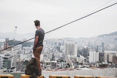 Man standing on seat against cityscape