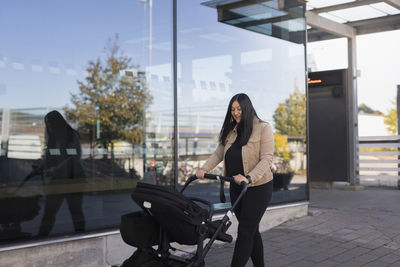 View of smiling mid adult woman on parental leave pushing pram