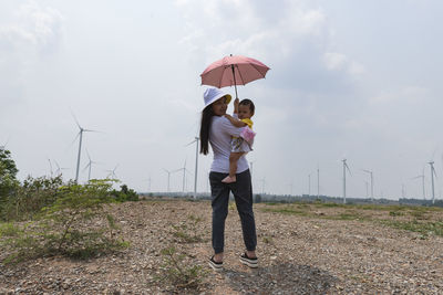 A young mother and her lovely little daughter are at a windmill field.