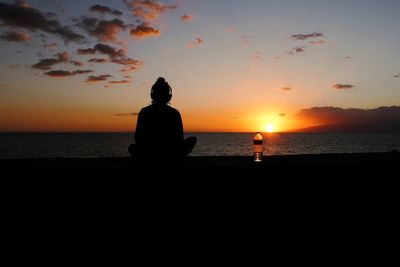 Silhouette man looking at sea against sky during sunset