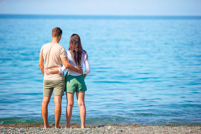 Rear view of couple standing at sea shore