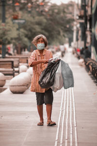 Full length portrait of woman standing on footpath