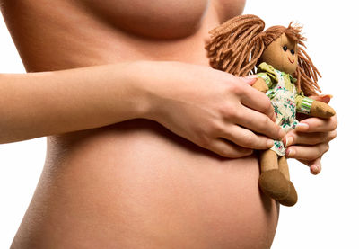 Midsection of naked pregnant woman with toy standing against wall
