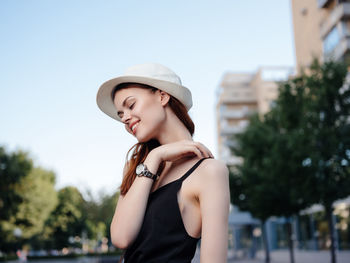 Side view of young woman wearing hat standing outdoors