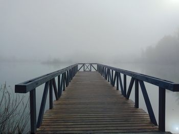 Pier on bridge against sky during foggy weather