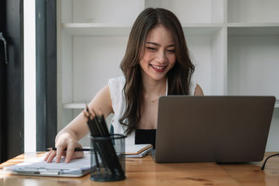Portrait of young woman using phone while sitting on table