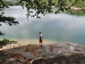 Full length of man standing on rock by lake