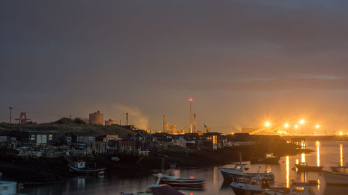 Sailboats moored at harbor against sky during sunset