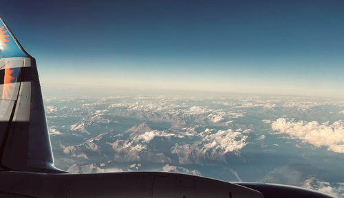 Airplane flying over landscape against sky