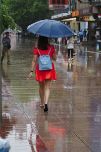 Full length of woman walking with umbrella on rainy day