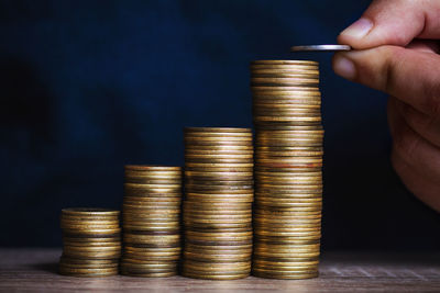 Close-up of hand stacking coins on table