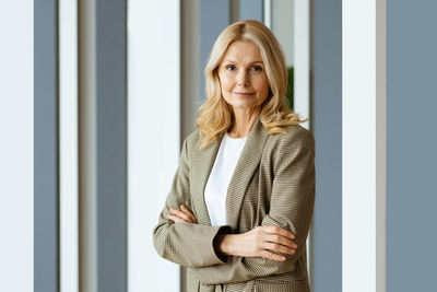 Portrait of young woman standing against wall