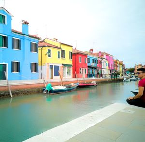 Houses by canal against sky in city