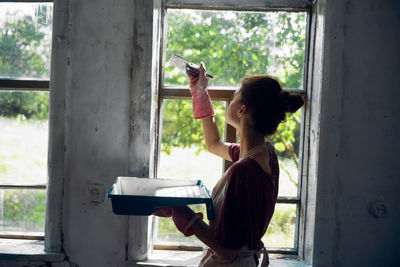 Side view of woman standing by window