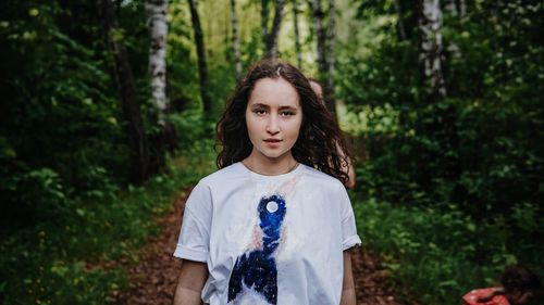 Portrait of woman standing against trees in forest