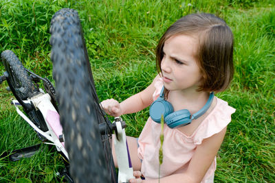 Side view of cute girl feeding bird on grass