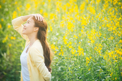 Smiling woman standing on yellow flowering field