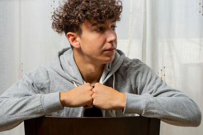 Young man looking away while sitting at home