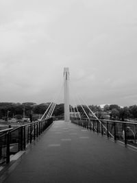 Footbridge over river in city against sky