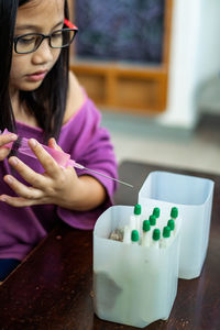 Child injecting organic fertilizer into small containers. fine motor skills activities for kids.