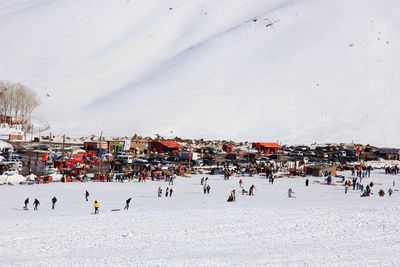 High angle view of people enjoying on snow field against mountain 