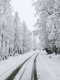 Road amidst snow covered landscape against clear sky