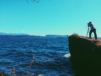 Rear view of man overlooking calm sea